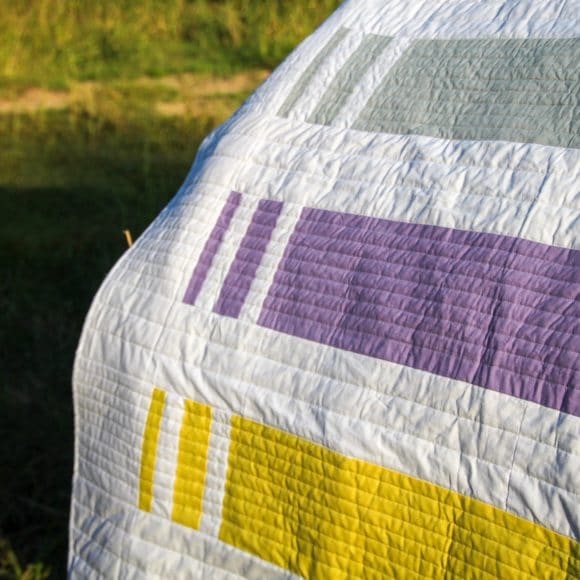 quilt patchwork rayé dans la nature, posé sur une botte de foin